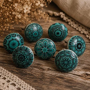 Può includere: Un gruppo di sette pomelli per mobili in ceramica turchese con disegni mandala neri. I pomelli, di forma sferica e finitura lucida, sono disposti su una superficie di legno rustico. Ogni pomello misura circa 4 cm di diametro.