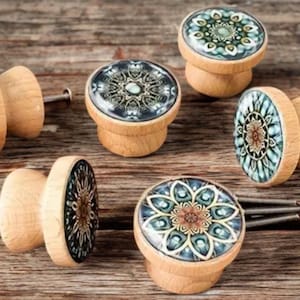 Peut inclure: Ensemble de boutons de meubles décoratifs en bois. Chaque bouton présente un motif rond et coloré, avec des nuances de bleu, vert et marron. Les boutons sont montés sur des bases en bois avec des vis métalliques.
