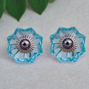 May include: Two blue glass cabinet knobs with a starburst design and a silver centre.
