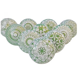 May include: A set of ten green and white ceramic knobs with intricate mandala designs. The knobs are round and have a glossy finish.