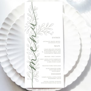 May include: A white menu card with a green floral design and the word "menu" in script. The menu is on a white plate with a scalloped edge. The menu lists entree, main, and dessert options.