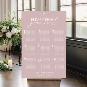 May include: A pale pink seating plan with the words "PLEASE FIND your seat" in elegant script. The chart is divided into nine sections, each with names. The event is for Christina's Baptism, January 12, 2025. A cross is at the top.