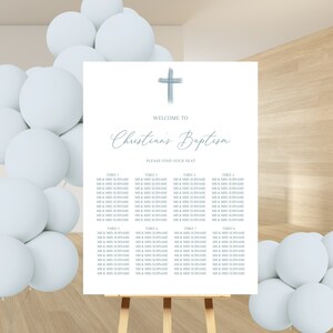 May include: A white seating chart with a blue cross at the top. The text "Welcome to Christian's Baptism" is written in cursive. The chart lists tables with names of guests.