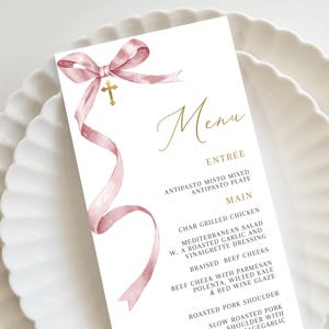 May include: A pink and gold menu card with a watercolor ribbon bow and a cross. The menu includes the following items: Antipasto Misto Mixed, Antipasto Plate, Char Grilled Chicken, Mediterranean Salad, Braised Beef Cheeks, Roasted Pork Shoulder.