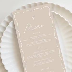 May include: A beige menu card with a white cross at the top and the word "Menu" written in cursive. The menu lists entrees, main courses, and desserts with descriptions of each dish.