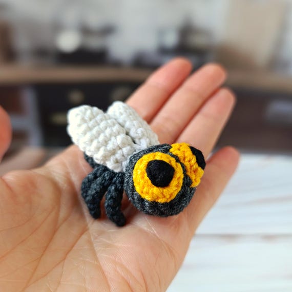 A hand-crocheted housefly in miniature — the specific grossness of the subject is what makes it brilliant as a gag/desk piece.