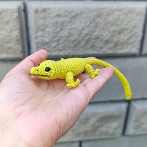 Peut inclure: Un lézard au crochet jaune vif fait à la main, avec des yeux noirs et une longue queue. Le lézard est fabriqué avec un point texturé, mettant en valeur son design détaillé. Un article unique et artisanal.