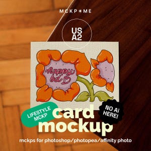 May include: A rectangular greeting card mockup featuring a cartoon illustration of two orange flowers with light purple centers. The left flower contains the pink cursive text "happy bd" and a small heart. Text overlays include "MCKP*ME", "US A2", "LIFESTYLE MCKP", "NO AI HERE!", and "card mockup".