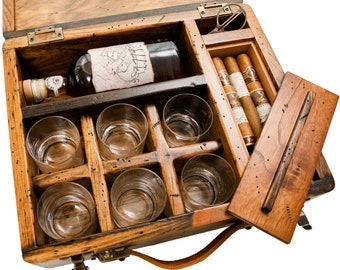 May include: Wooden box with a leather handle, containing a bottle of spirits, six glasses, and a box of cigars. The box is open and the lid is propped up.