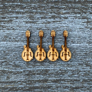 May include: Four wooden cutout mandolin shapes, each with a different design, arranged in a row on a gray wooden background.
