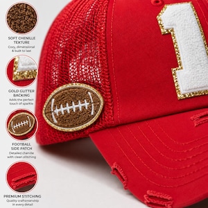 May include: A red trucker hat featuring a white chenille number one patch with a gold glitter border on the front panel. The side displays a brown chenille football patch with white stitching and a gold glitter border. The brim has distressed detailing.
