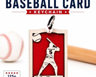 May include: A custom baseball card keychain featuring a light wood frame with a red background. The design includes a silhouette of a baseball player with the name Thangamani and number 5, plus the text Nathan Thangamani and Hinsdale Devils White 2022.