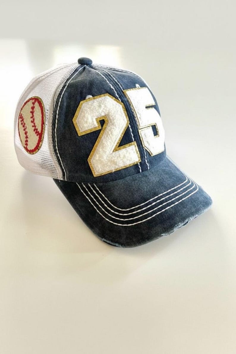 May include: A blue baseball cap with a white mesh back and a baseball patch. The cap features the number 25 in white with gold trim. The brim has white stitching.