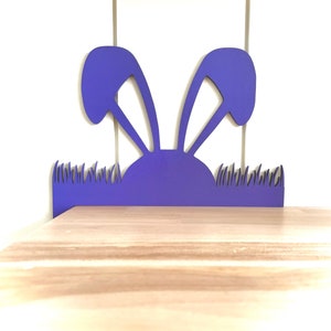 May include: Purple bunny rabbit cutout with grass at the bottom. The bunny is a silhouette with no details.