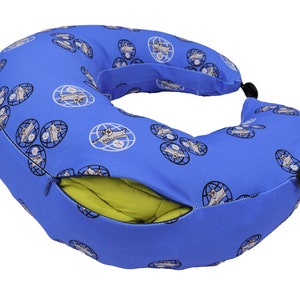 Op de afbeelding: Een blauw reisnekkussen met een ritsvak en een groen binnenkussen. Het kussen heeft een herhalend patroon van een wereldbol met een cartoondier erop.