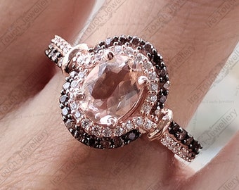 May include: A rose gold ring featuring a large oval morganite gemstone, surrounded by a halo of smaller diamonds and brown diamonds. The ring has a double band design.