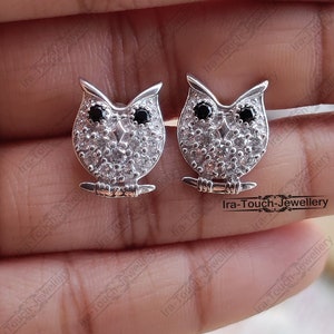 May include: A pair of silver owl stud earrings with black and white cubic zirconia stones.