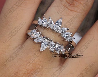 Puede incluir: Un anillo de plata con una montura de diamante de forma marquesa. El anillo está engastado con varios diamantes en un diseño curvo.