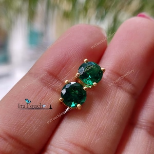 May include: A pair of gold stud earrings with round green gemstones.
