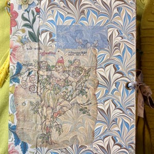 May include: A rectangular journal with a marbled blue, brown, and white cover. The spine features a floral pattern. A central collage includes a drawing of a figure among roses with the text "and with eglantine." and "Midsummer Night's Dream, Act ii., Sc. 1".
