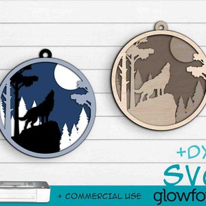 May include: Two round wooden ornaments with a wolf howling at the moon in a forest scene. One ornament is blue with a white moon and the other is brown with a white moon. Both ornaments have a hole at the top for hanging.