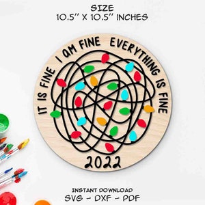 May include: A 10.5 inch round wooden ornament with a black and white design of tangled Christmas lights. The lights are red, green, blue, and yellow. The text "It is fine I am fine everything is fine" is written around the outside of the ornament. The year 2022 is written in the center of the ornament.