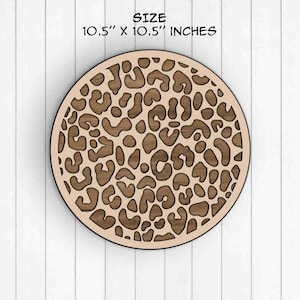 May include: A round wooden wall decor with a leopard print design. The decor measures 10.5 inches in diameter.