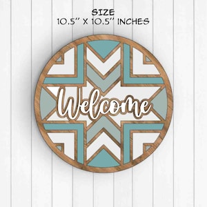 May include: A round wooden welcome sign with a geometric pattern in shades of blue and white. The sign measures 10.5 inches in diameter.