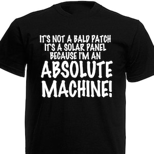 May include: Black t-shirt with white text. The text reads: "IT'S NOT A BALD PATCH IT'S A SOLAR PANEL BECAUSE I'M AN ABSOLUTE MACHINE!" The shirt has short sleeves and a crew neck.