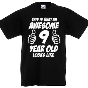 May include: Black t-shirt with white text that says "This is what an awesome 9 year old looks like" with thumbs up on either side of the number 9.