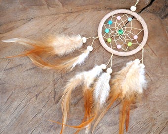 May include: A beige dreamcatcher with a green and pink beaded web and brown feathers.