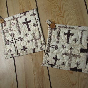 May include: Two beige quilted pot holders with brown cross designs and brown buttons.