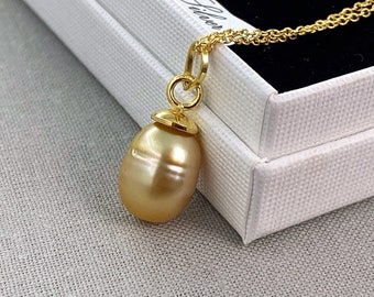 May include: A gold chain necklace with a golden pendant featuring a large, golden pearl.