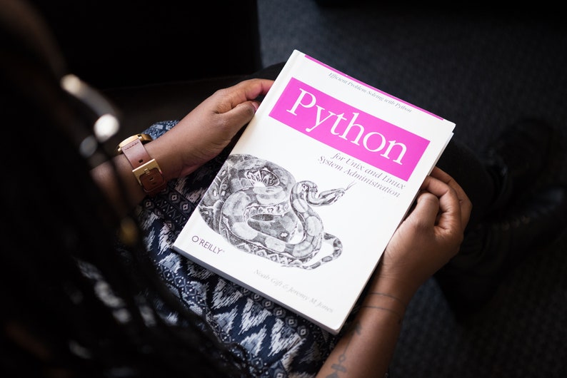 Puede incluir: Un libro blanco con un t&iacute;tulo rosa que dice "Python for Unix and Linux System Administration" de O'Reilly. El libro presenta una ilustraci&oacute;n en blanco y negro de una serpiente.