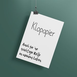 Puede incluir: Una hoja de papel blanca con el texto "Kloppapier" y "Auch so 'ne wichtige Rolle in meinem Leben." colgada de un clip sobre un fondo verde.