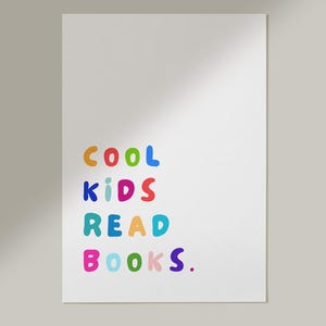 Könnte beinhalten: Weißes Poster mit dem Text "COOL KIDS READ BOOKS" in bunten, abgerundeten Buchstaben. Die Wörter sind in einer verspielten Schriftart gehalten, wobei jedes Wort eine andere Farbe hat: Orange, Blau, Rot, Türkis und Pink.
