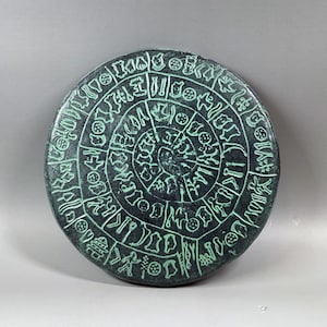 Disco de terracota antiguo patinado verde Reproducción griega Disco de Festos Artefacto cultural griego Caja de museo Disco minoico Monumento con letras