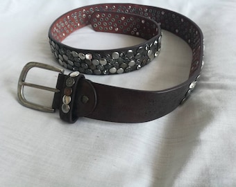 Bruine leren riem met metallic zilveren oogjes.