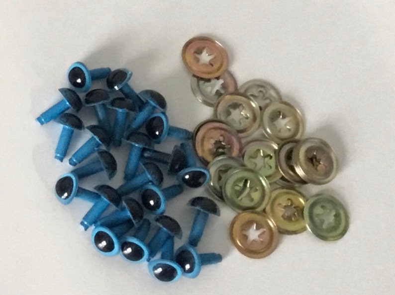 May include: A pile of blue plastic safety eyes with black pupils and metal washers. The safety eyes have a post on the back for attaching to fabric.
