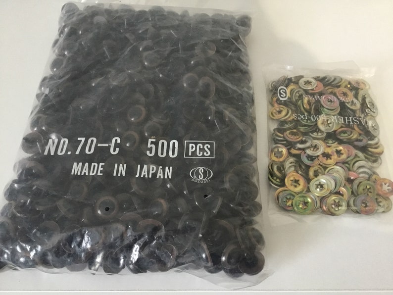May include: Two bags of black plastic buttons. The bag on the left contains 500 black plastic buttons and has the text "NO.70-C 500 PCS MADE IN JAPAN" printed on it. The bag on the right contains a variety of metal washers.