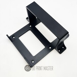 May include: Black 3D printed hard drive mount with a handle. The mount has a rectangular opening for a hard drive and is designed to be mounted to a wall or other surface.