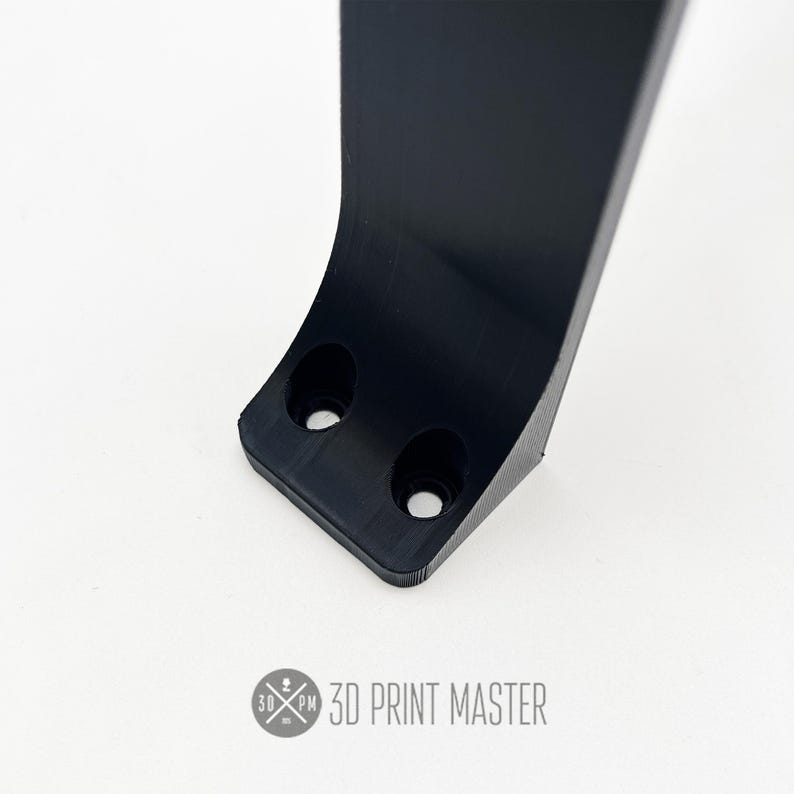 May include: Close-up of a black plastic 3D printed part with two screw holes. The part has a curved shape and a smooth surface.