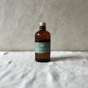 May include: A brown glass bottle with a gold lid and a green label that reads "rhubarb & mint KITCHEN SCENTS".