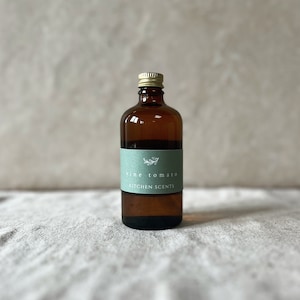May include: A brown glass bottle with a gold lid and a green label that says "vine tomato KITCHEN SCENTS".