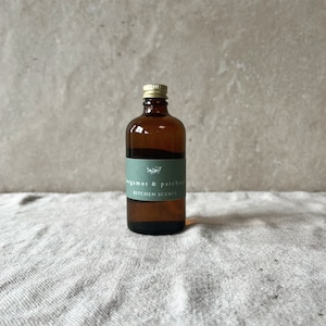 May include: A brown glass bottle with a gold lid and a green label that reads "bergamot & patchouli kitchen scents".
