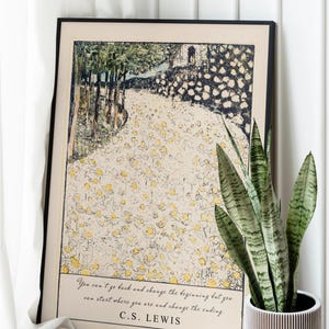 May include: A black framed print with a vintage illustration of a path through a field of white flowers. The quote "You can't go back and change the beginning but you can start where you are and change the ending." by C.S. Lewis is printed below the illustration.