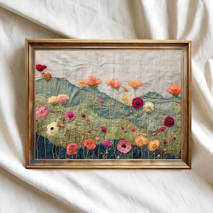 May include: A framed textile art piece featuring a colorful field of embroidered flowers. The flowers are in shades of pink, orange, and red, with green stems and leaves. The background depicts a landscape with blue and gray hills. The frame is a warm brown color.