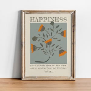 Op de afbeelding: Een ingelijste print met een blauwe achtergrond en een gestileerd oranje bloemenontwerp. De tekst "HAPPINESS not in another place but this place... not for another hour, but this hour. Walt Whitman" is onder het bloemenontwerp gedrukt.