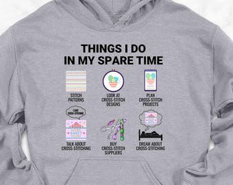 May include: A light gray hoodie with the text "THINGS I DO IN MY SPARE TIME" and illustrations of cross-stitch activities. The hoodie is surrounded by accessories like shoes, jeans, and a backpack.