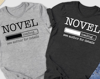 May include: Two t-shirts, one gray and one dark gray, with the word "NOVEL" printed on them. Below the word is a loading bar graphic and the text "loading... see author for details". The shirts are displayed with jeans, shoes, and accessories.